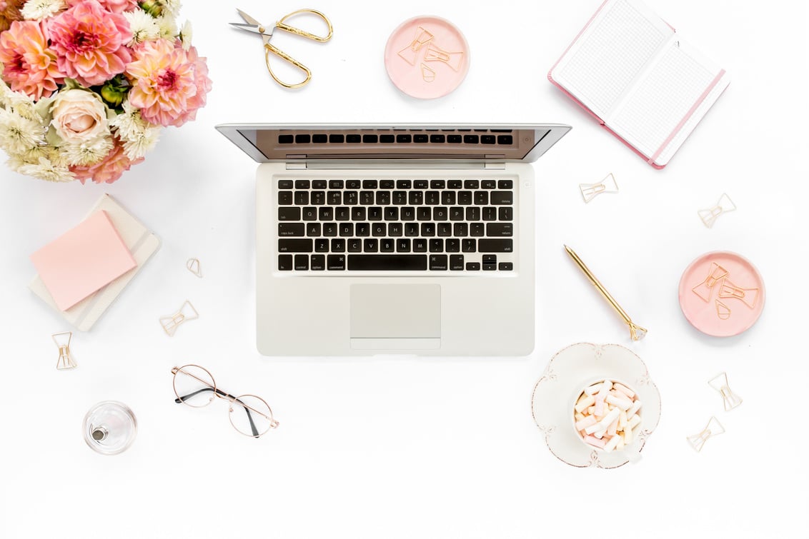 Flat lay women's office desk. Female workspace with laptop, pink peonies bouquet, accessories on white background. Top view feminine background.